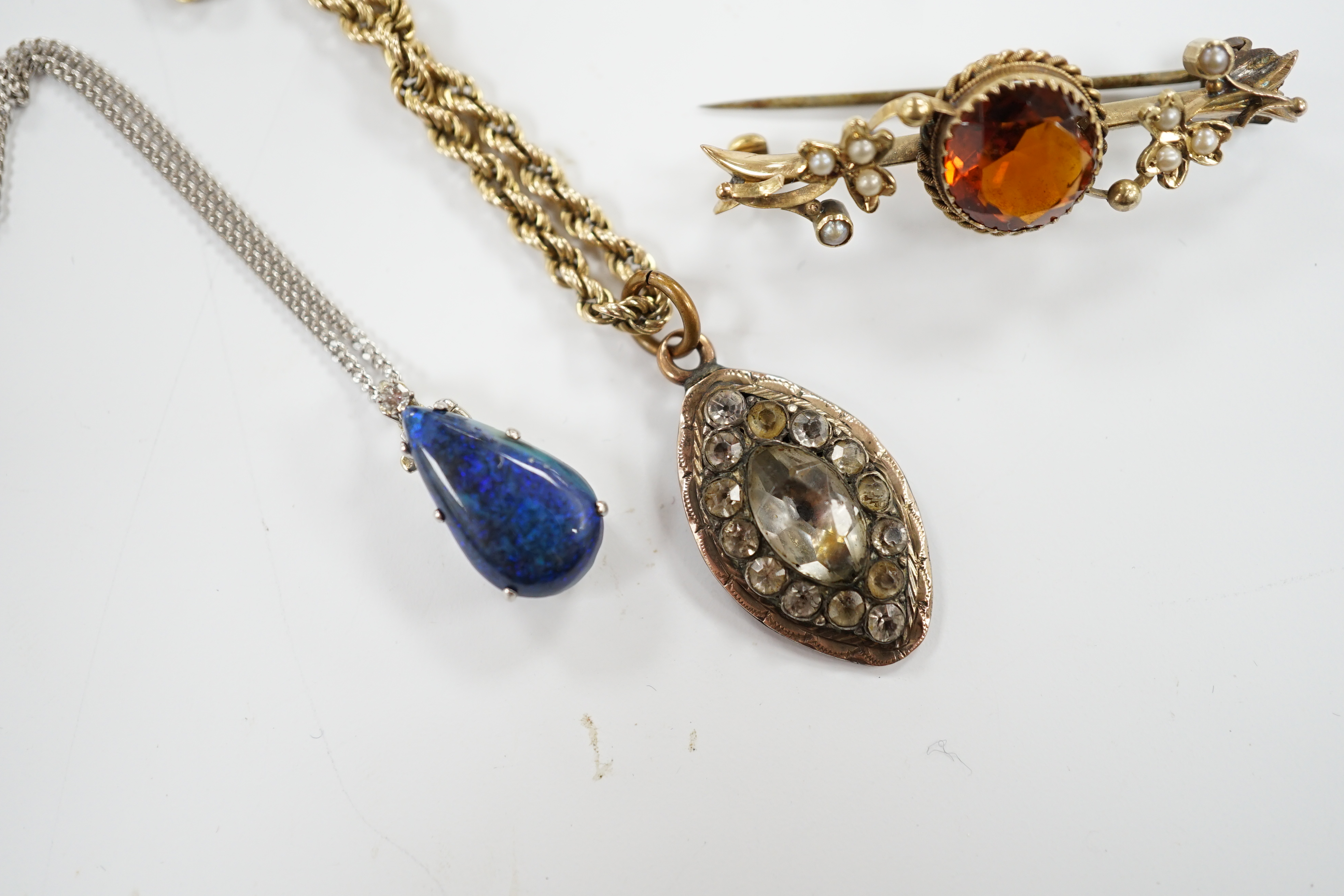 A 15ct and citrine set brooch, paste set pendant on a 9ct gold rope twist chain and a modern white metal and simulated opal set pendant, on a 9ct white gold chain.
